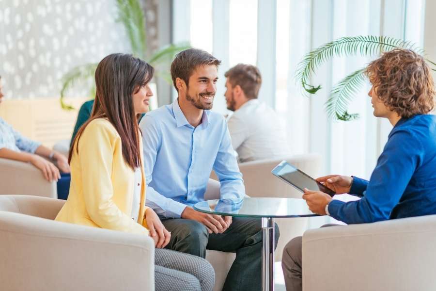 Un couple échange avec un conseiller financier pour discuter du montant de leur prime d'assurance.